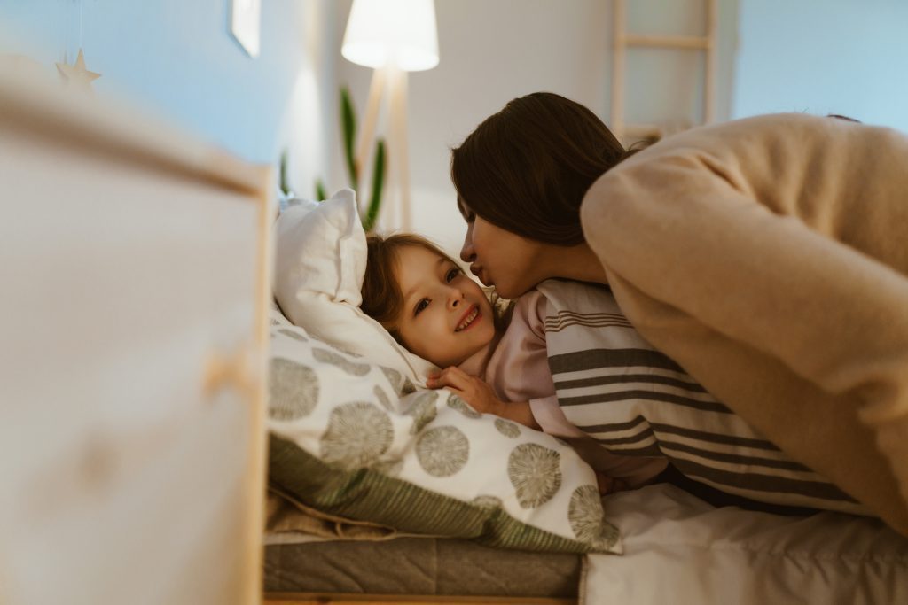 Mother kisses her daughter before bedtime